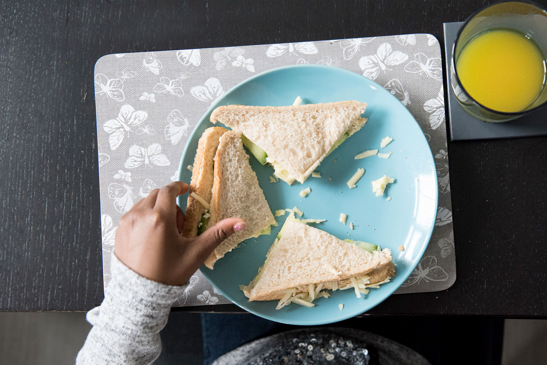 Aerial view of child eating a cheese and cucumber sandwich