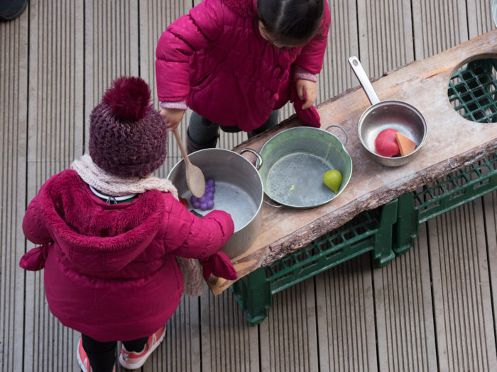 Children playing with plastic cooking equipment and food