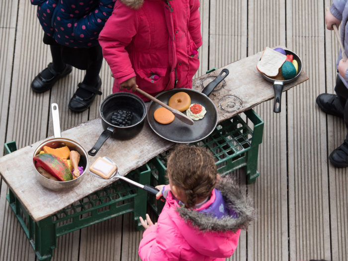 Children playing with toy food and cooking equipment