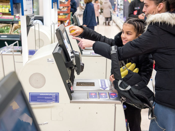 Mum and daughter at self-checkout in a supermarket