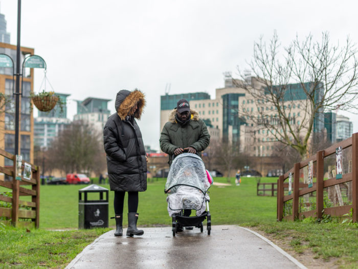Parents walking with their child in a pram in the rain