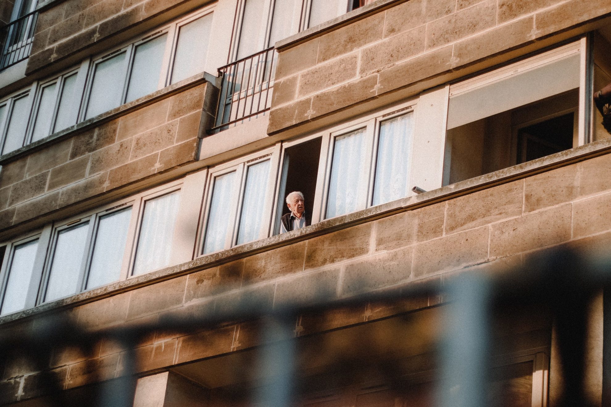 An older man looking out the window in Paris, France