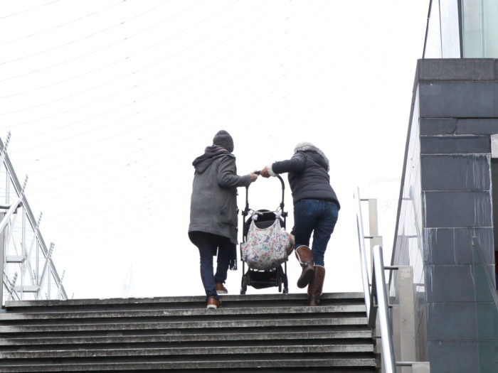 Parents lifting a pram up stairs