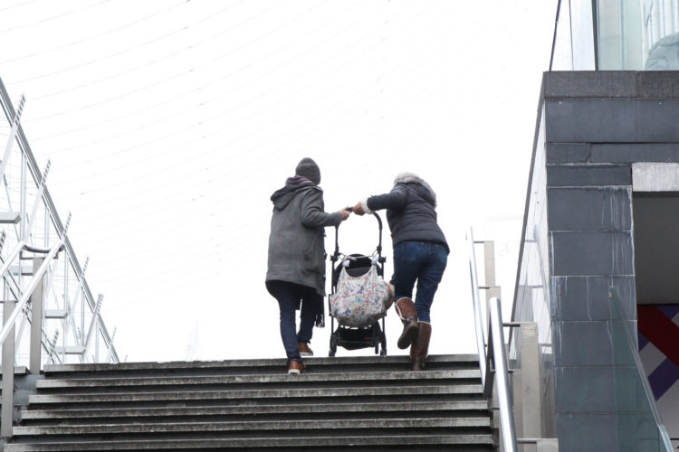 Parents lifting a pram up stairs