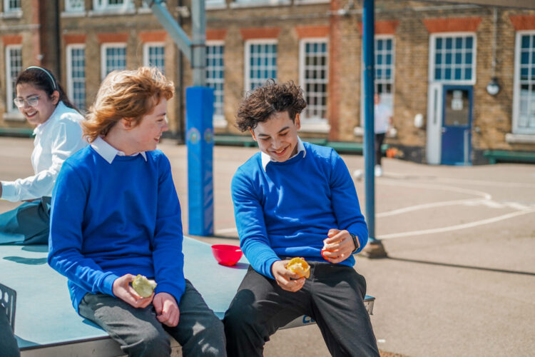 Teens chatting and snacking in an outside playground area