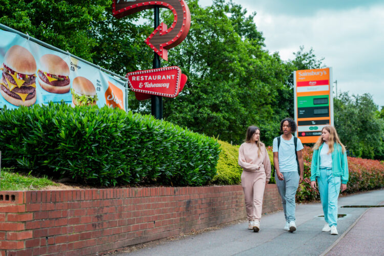 Teenagers walking past fast food signage