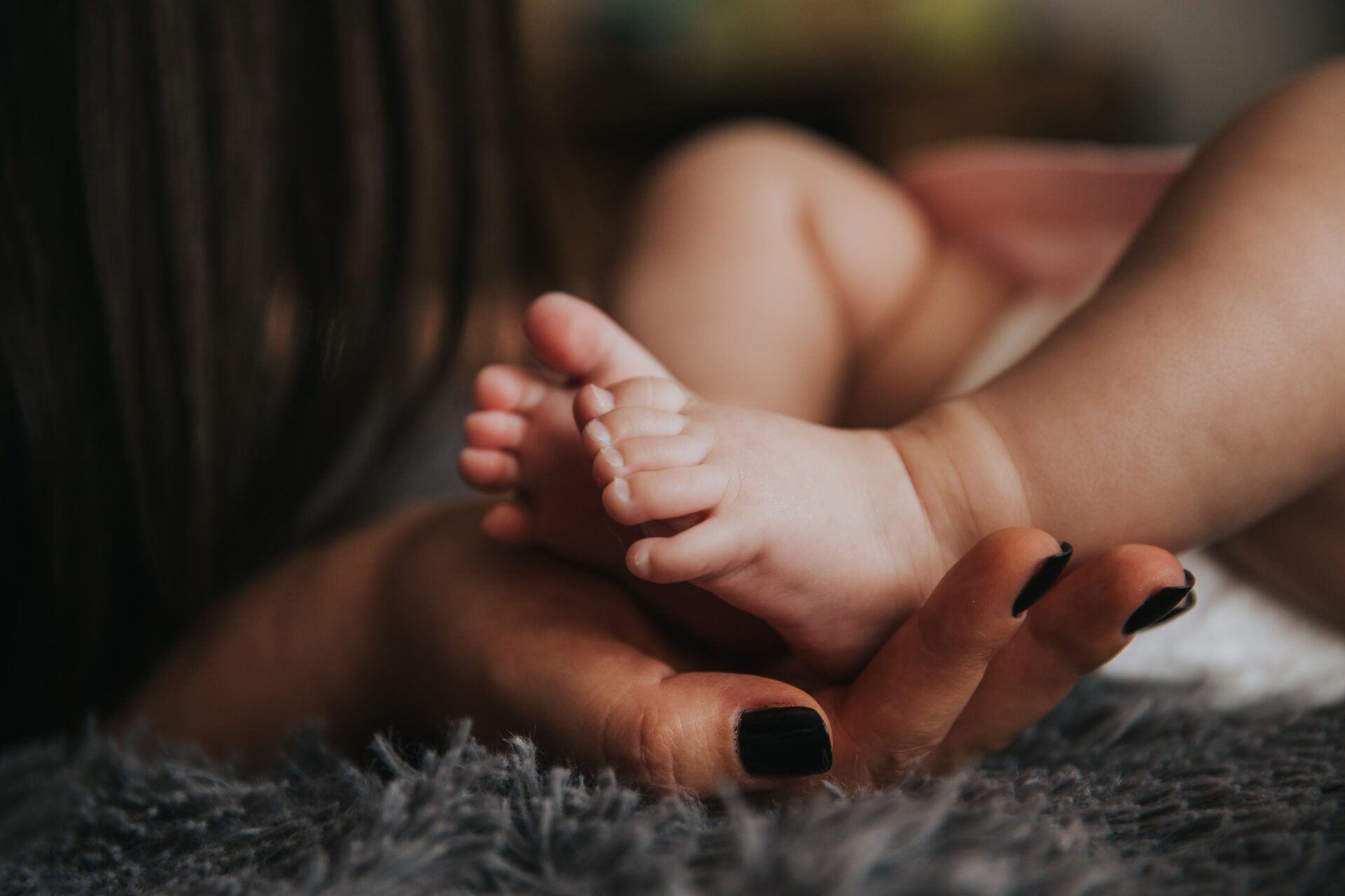 An infants foot being held by their mother.