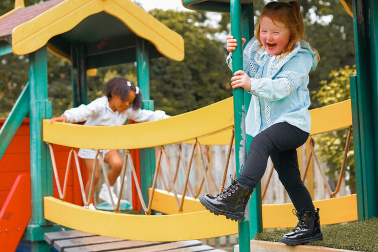 Two children laughing on playground bridge