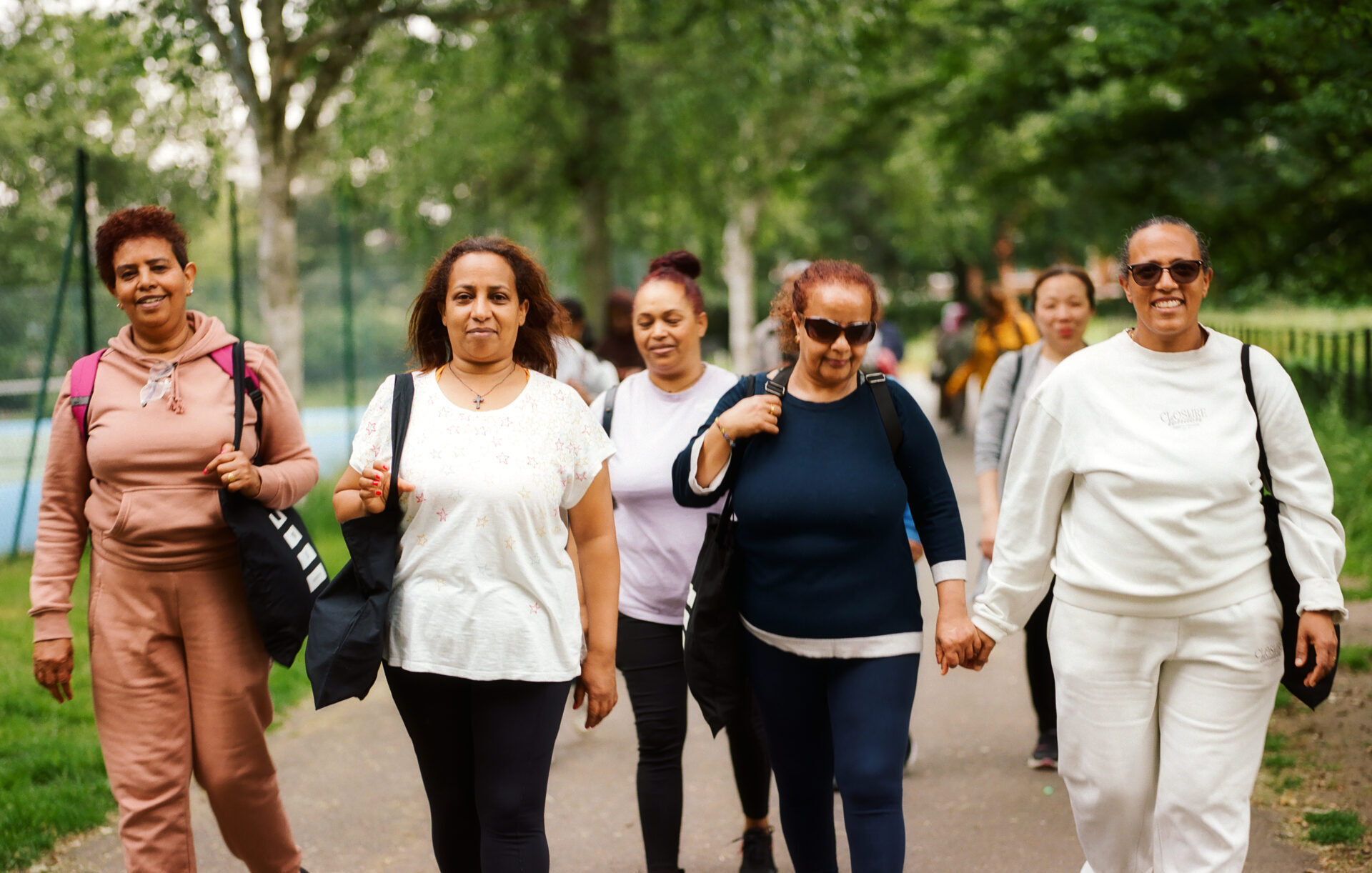 A group of people walking together along a tree-lined park path. Photograph by Francis Augusto