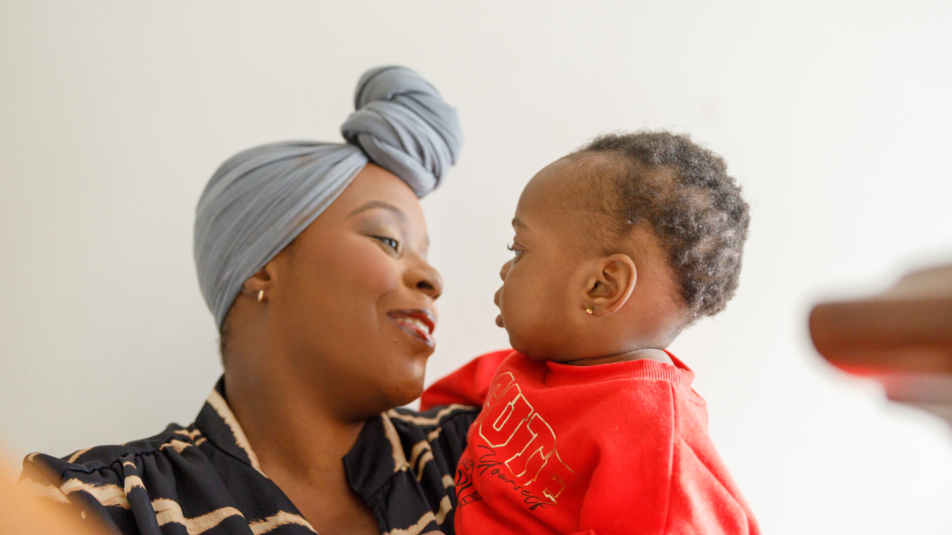 Mother and child smiling at each other, close-up. Photograph by Jade Reynold-Hemmings