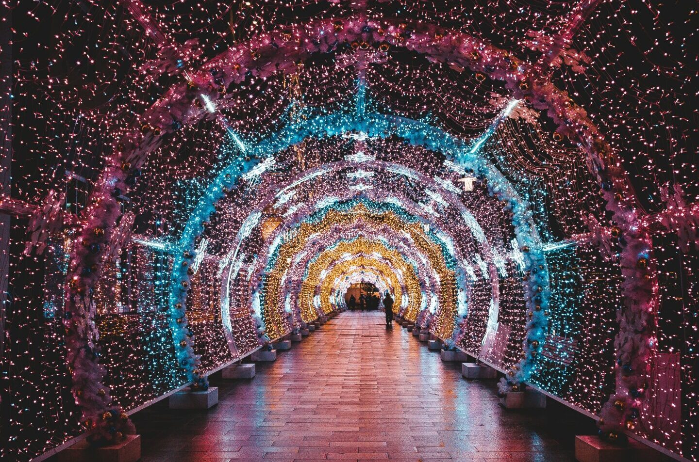 Colourful lights illuminate a dark tunnel in an arc shape. Photograph by Eric Rai.