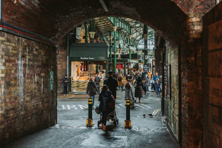 Shoppers at Borough Market, viewed through the brick arch of a bridge. Photograph by Bruno Martins