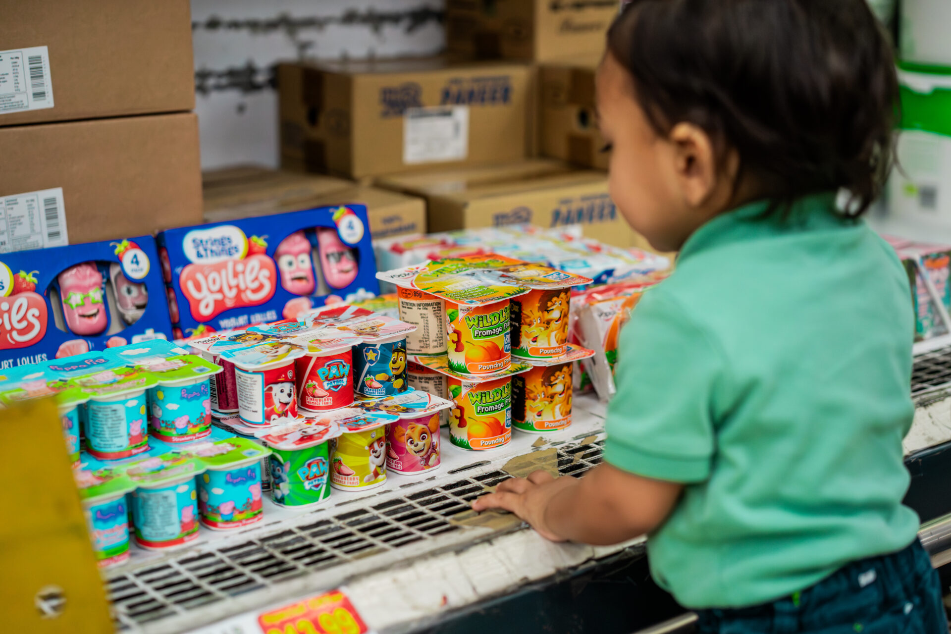 A child is looking at yoghurt pots in a supermarket.