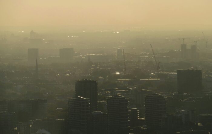 An aerial view of various buildings in London. There is a hazy sunset.