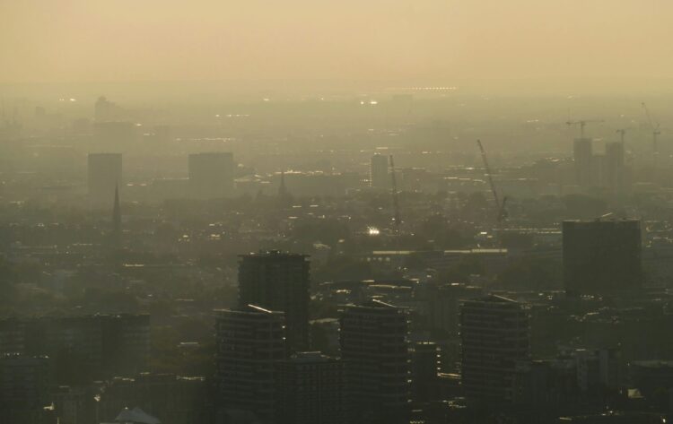 An aerial view of various buildings in London. There is a hazy sunset.