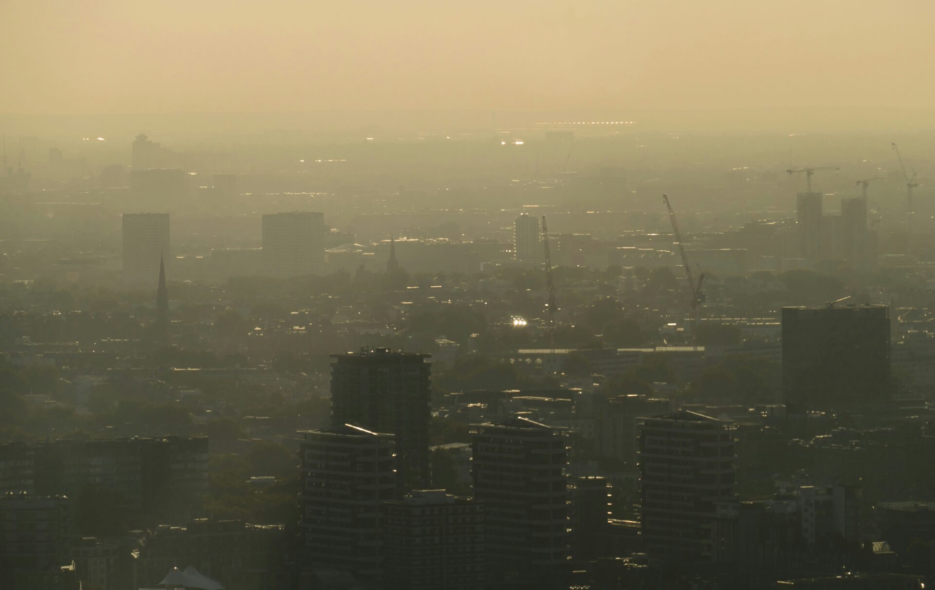 An aerial view of various building in London. There is a hazy sunset.