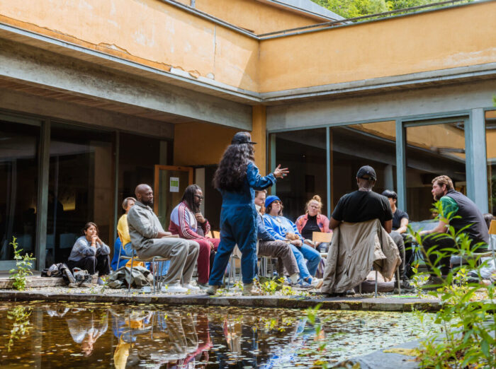 People are sitting on chairs in an outside space and talking.