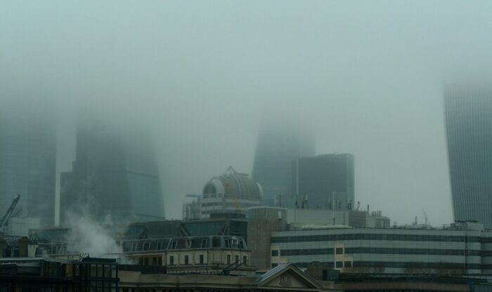 The London city skyline with tall buildings partly obscured with haze. Photo by Kevin Mueller.