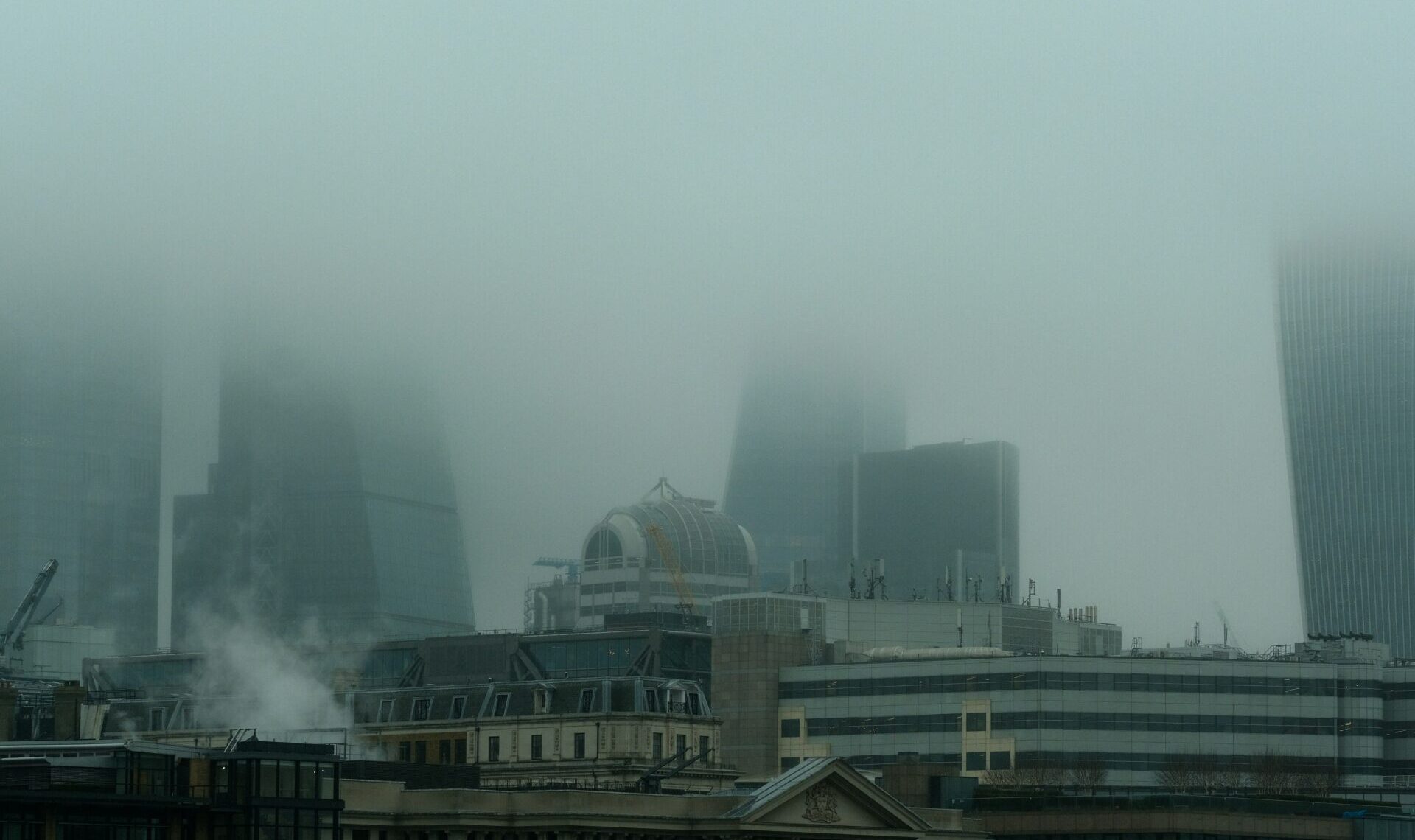 The London city skyline with tall buildings partly obscured with haze. Photo by Kevin Mueller.