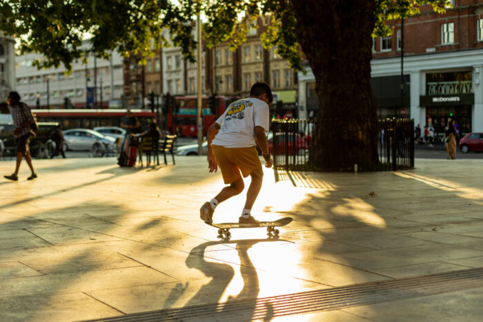A%20person%20skateboarding%20on%20a%20paved%20area.%20In%20the%20distance%2C%20there%20are%20some%20shops%20and%20restaurants.