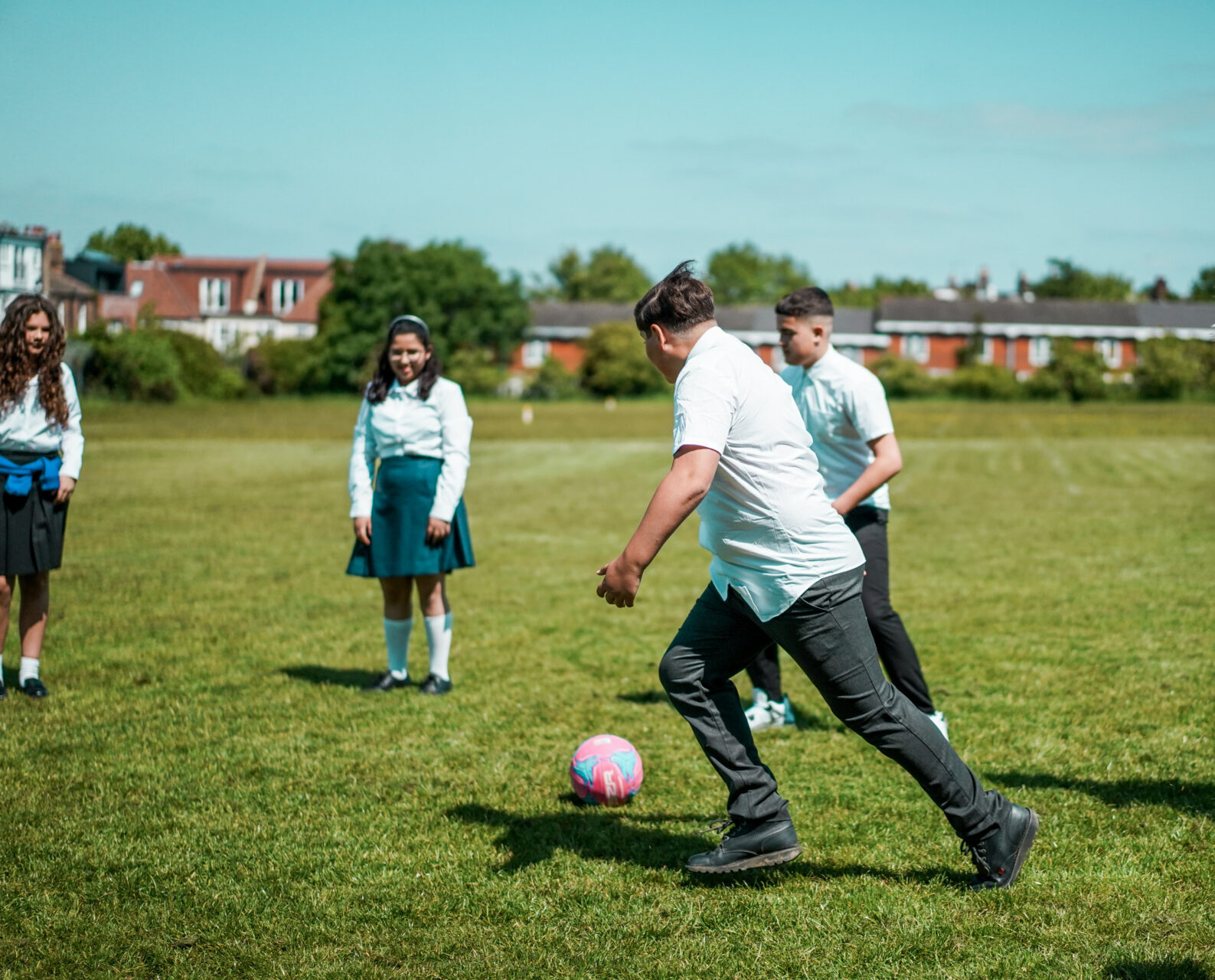 Children are playing football in a grassy field.