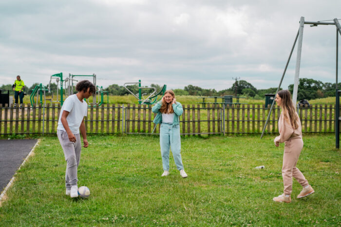 Three%20children%20are%20playing%20football%20on%20a%20patch%20of%20grass