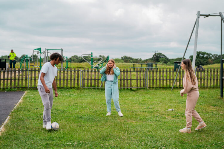 Three children are playing football on a patch of grass