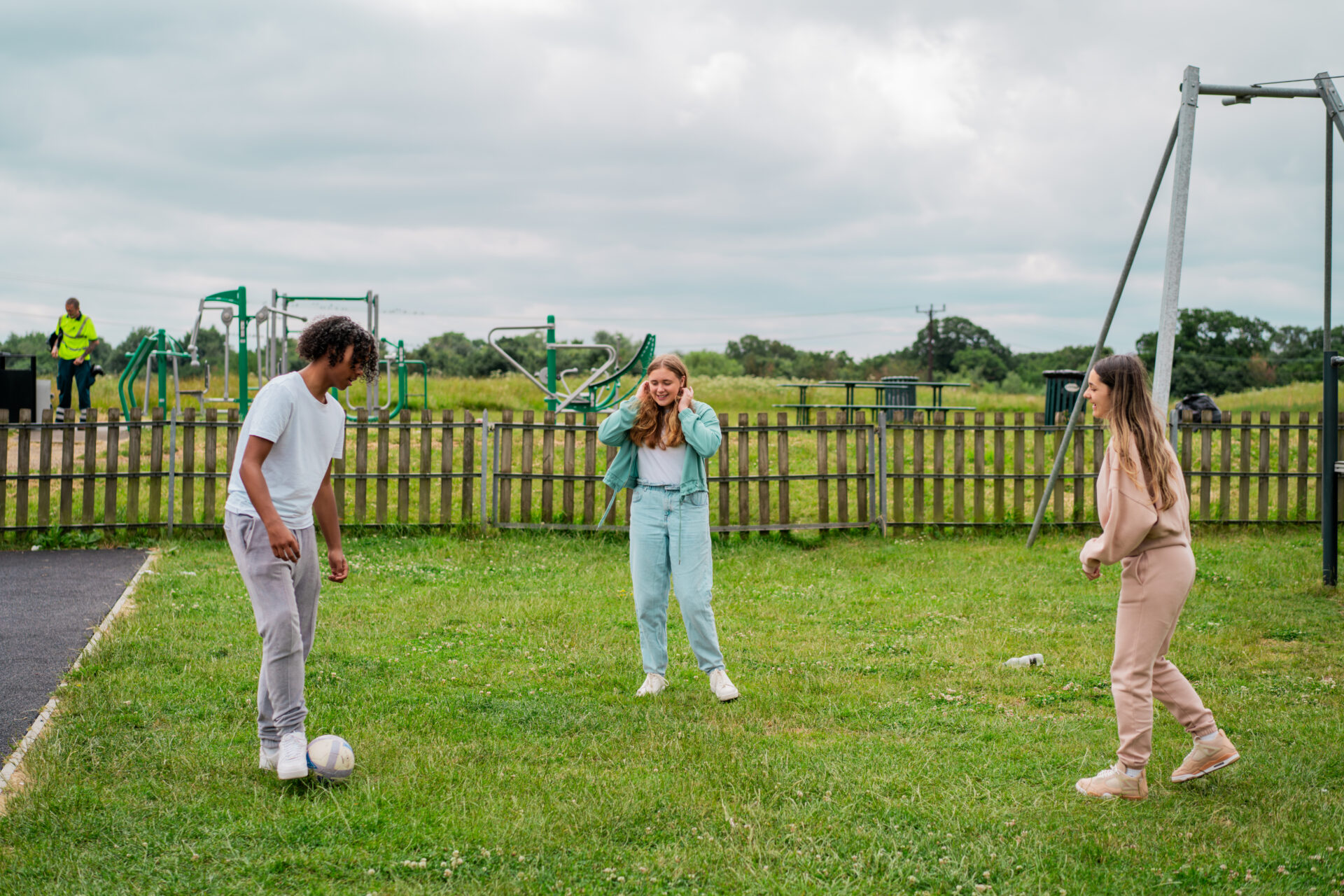 Three children are playing football on a patch of grass